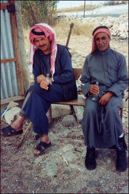 Two villagers enjoy a cold bottle of Coca-Cola outside a small shop. Near El-Greyat, Beni-Hamida Mountains, Jordan.